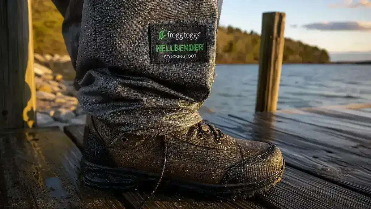 Close-up of a stockingfoot wader's neoprene bootie tucked into a worn felt-soled wading boot on a wooden dock